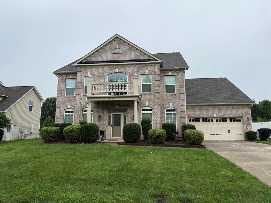 Suburban home with expert curb appeal featuring a manicured lawn and shaped ornamental shrubs.